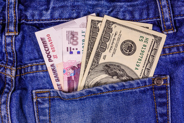 Different american and russian banknotes in a pocket of blue jeans