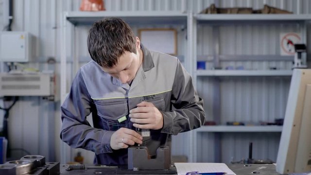 master is measuring holes in a detail in a laboratory of factory of production tools, using digital device