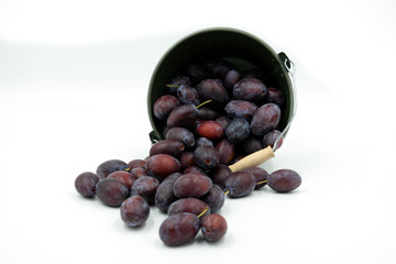 Zwetschgen fallen aus einem kleinen dekorativen Eimer.