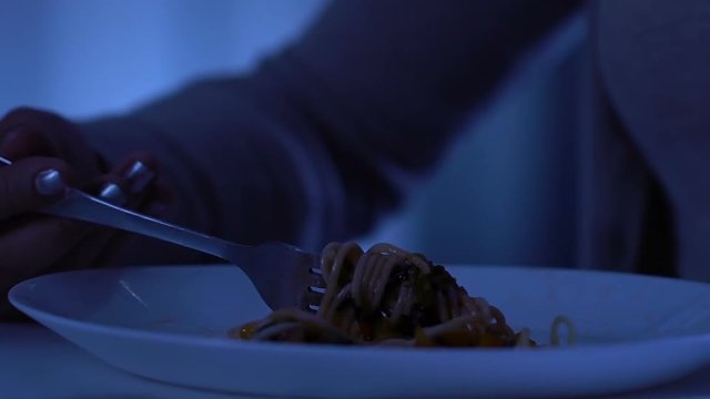 Hungry homeless female eating spaghetti and crying about her life, bulimia