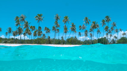 HALF HALF: Glassy ocean water splashes over the camera filming exotic island.