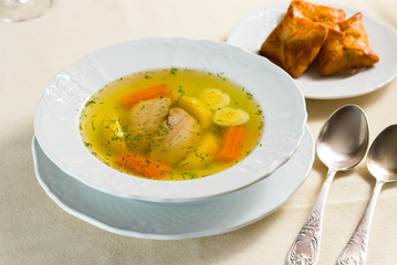 chicken soup with spices and vegetables in a plate on a table with a tablecloth with baking, egg, carrot, potato