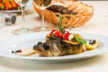 Baked trout with caviar and vegetables and dressed with parmesan sauce on a plate