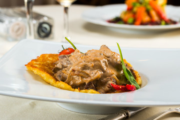 beef stroganoff on pancakes made from cathofiot with tomatoes and peppers, pancakes from potatoes