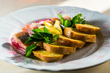 Herring with potatoes decorated with herbs with lemon and olive, cold appetizers for alcoholic beverages