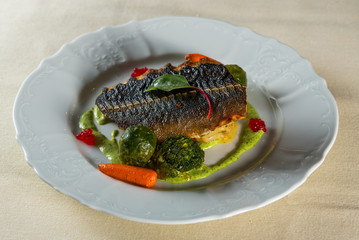 fish fillet with vegetables on a white plate