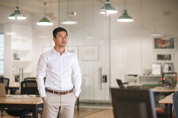 Asian businessman standing in an office thinking up new ideas  