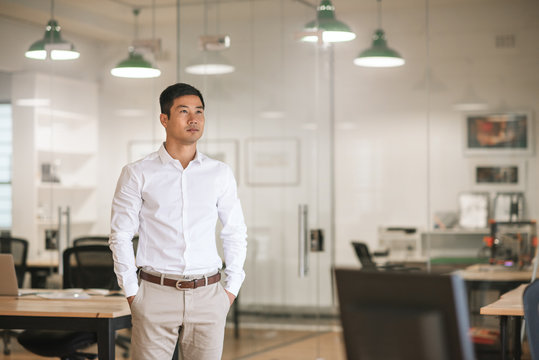 Asian Businessman Standing In An Office Thinking Up New Ideas  