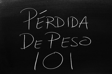 The words Pérdida De Peso 101 on a blackboard in chalk.  Translation: Weight Loss 101