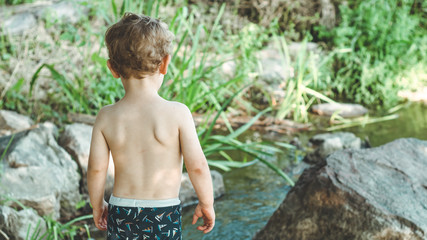 Happy child, little boy playing, pensive look and holding in hands the stick outdoors. Space for Text. Retro toned. Summer