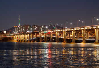Fototapeta premium SEOUL, SOUTH KOREA - JAN 22, 2018: Banpo bridge and N Seoul tower at night with reflection on frozen river