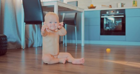 Little naked blond babe is sitting on the floor in an apartment and is looking at the camera - Powered by Adobe