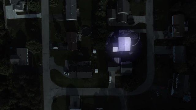 A top down bird's eye view of a spotlight shining on random homes at night in a typical Pennsylvania neighborhood. Alien scanning concept.	