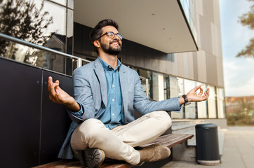 Businessman - mentally preparing for business meeting. Sitting in meditation pose in front of...