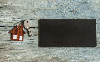 blank blackboard and symbol of the house with silver key on vintage wooden background