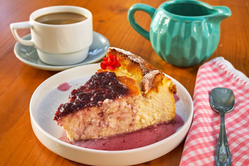 Delicious homemade cheese cake with strawberry jam and a cup of coffee