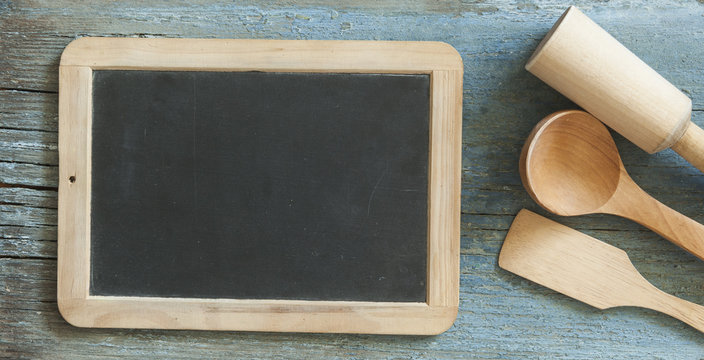 Kitchen utensils with copy space and blank blackboard on wood background