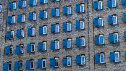 Side of a old building. Bricks wall with windows and shades, old brick building with shades open.
