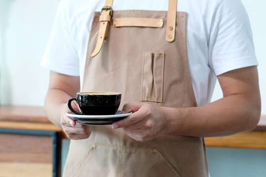 Barista hand holding a coffee cup at cafe background, small business owner, food and drink industry