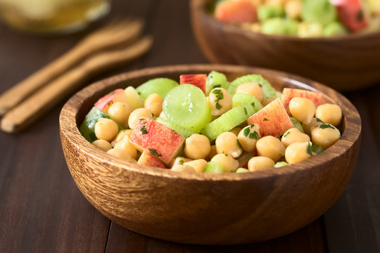 Fresh vegan chickpea, celery, grape and apple salad with parsley in wooden bowls, photographed with natural light (Selective Focus, Focus in the middle of the first salad)