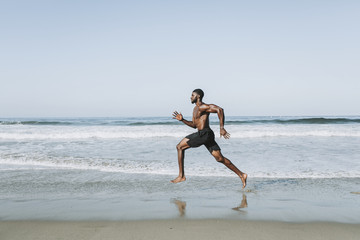 Fit man running at the beach - Powered by Adobe