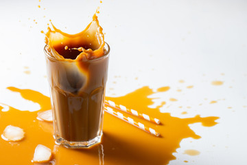 Iced latte coffee splash with ice cubes and roasted beans on a white background. With copy space