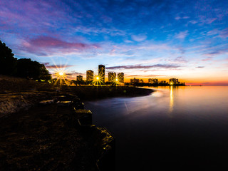Gorgeous long exposure sunset photograph looking across Lake Michigan at Foster Beach to the highrise buildings and colorful blue purple and orange colored sky on the horizon.
