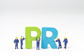 PR, Public Relations concept, miniature people staff help building color wooden letters forming...