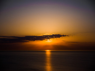 Beautiful sunrise photograph with vibrant orange and yellow colors over the dark waters of Lake Michigan in Chicago with layers of clouds in the sky above.