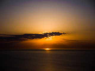 Obraz premium Beautiful sunrise photograph with vibrant orange and yellow colors over the dark waters of Lake Michigan in Chicago with layers of clouds in the sky above.
