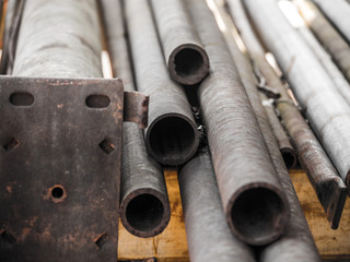 Close up photograph of the ends of a pile of random weathered and rusted pieces of steel, iron and galvanized round pipe or tube steel sections or extrusions making a great industrial type background.