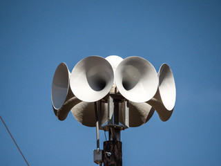 Close up photograph of several multi directional round amplified emergency siren  or noon time horns on top of a wooden pole in a small town in Wisconsin. - obrazy, fototapety, plakaty