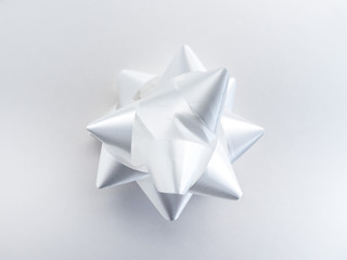 Close-up photograph of manufactured shiny white ribbon bow centered and isolated on a white background.