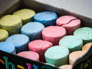 Obraz na płótnie Canvas Close up background photograph image of colorful sidewalk chalk including red, green, blue, yellow and orange organized in rows by color.