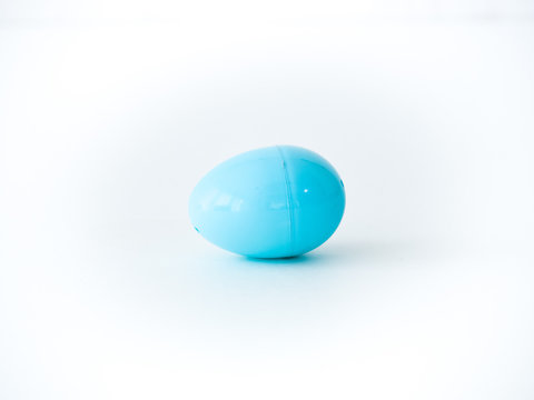 A closeup photograph of a single light blue plastic Easter egg that comes apart for toys, candy or money during egg hunts isolated on a white background with open space around it.