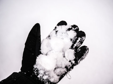 A Close Up Image Of A Black Fabric Water Resistant Insulated Winter Sports Glove With Snow In The Palm Of The Hand In Winter.