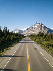 Aerial view of a scenic road in the Canadian Rockies during a vibrant sunny summer day. Taken in Icefields Parkway, Banff, Alberta, Canada.