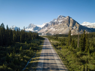 Aerial view of a scenic road in the Canadian Rockies during a vibrant sunny summer day. Taken in Icefields Parkway, Banff, Alberta, Canada.