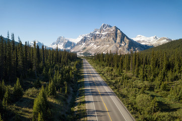 Aerial view of a scenic road in the Canadian Rockies during a vibrant sunny summer day. Taken in Icefields Parkway, Banff, Alberta, Canada.