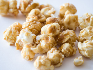 Close up macro photograph of isolated pile caramel popped popcorn kernel pieces at center of image with white space below for delicious looking background or wallpaper image.