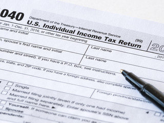 Close up photograph of United States 1040 individual income tax return form with a black ballpoint pen perfect for tax day or tax season background or wallpaper image.