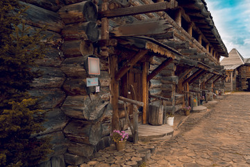 Fototapeta na wymiar Two-storey wooden log house with paved wooden road