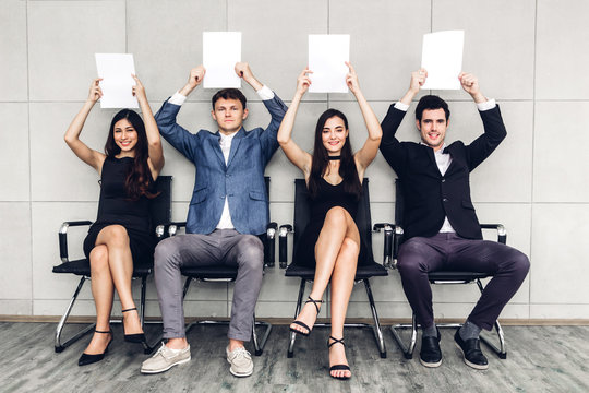 Group of business people holding paper while sitting on chair waiting for job interview against wall background