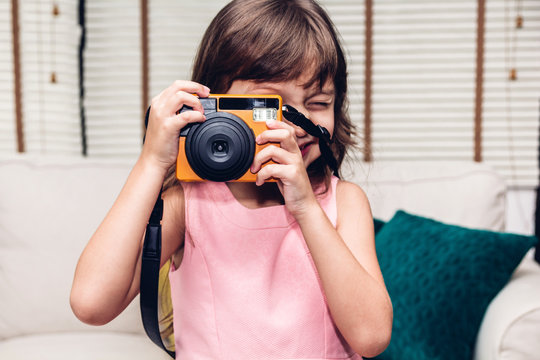 Little cute girl taking a picture with vintage camera at home