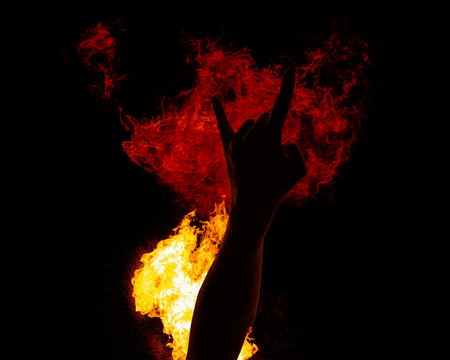 Hand giving rock against fire blast, heavy metal sign on flame, isolated on black
