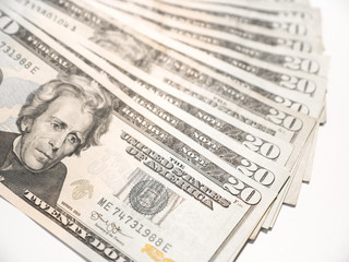 Close up photograph of real US twenty dollar bills fanned out on white table top background.