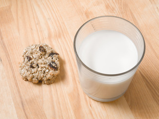 Homemade delicious oatmeal raisin cookies and a glass of milk for the Christmas holiday with wood butcherblock background.