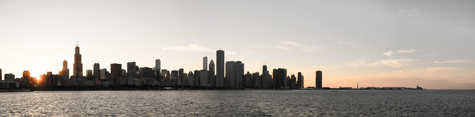 Fototapeta premium Chicago skyline panorama picture during beautiful sunset with building silhouettes and rippling waves of Lake Michigan water in the foreground