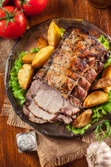 Roasted pork loin with baked potatoes and herbs