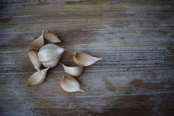 Uncleaned garlic heads with roots and stems on a wooden painted light background. Copy space.